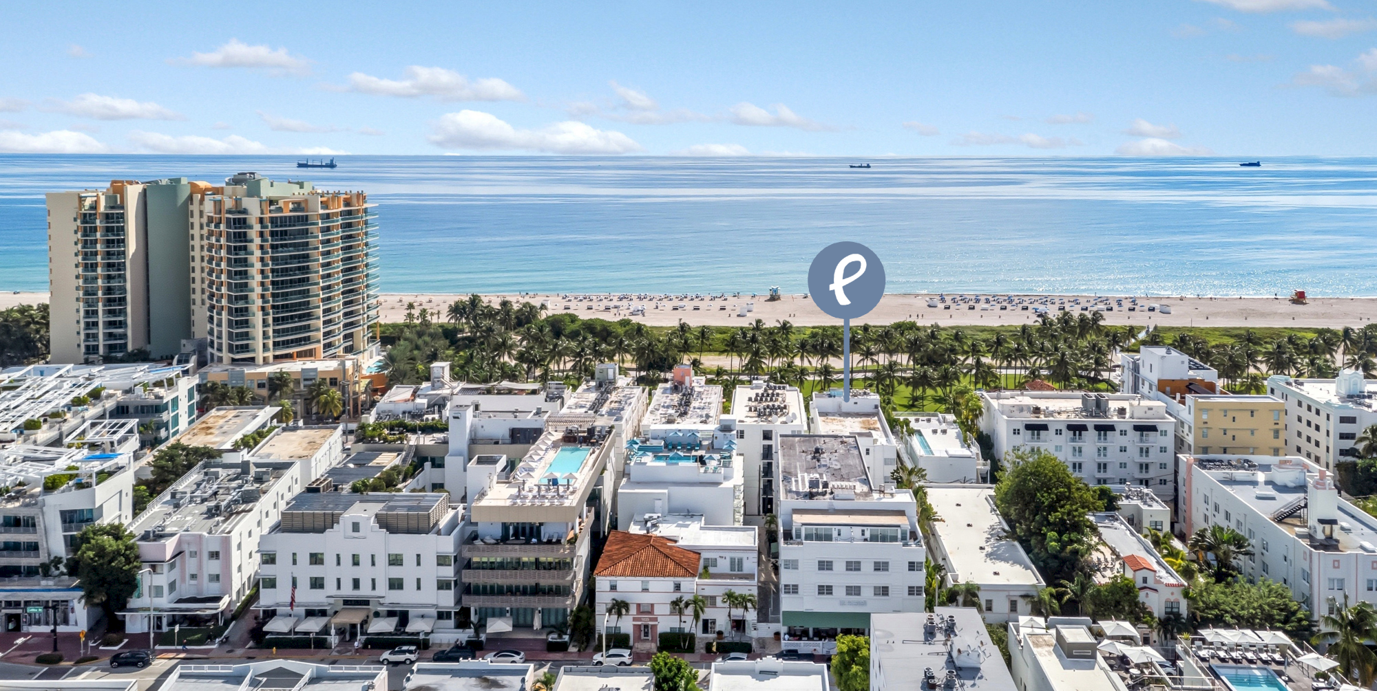 A coastal cityscape with buildings, a beach, and the ocean in the background, under a partly cloudy sky.