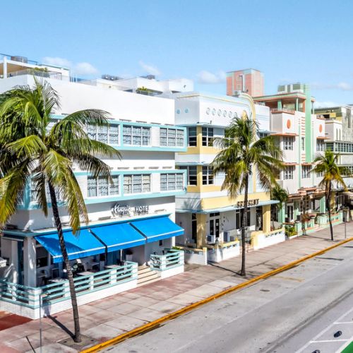 A vibrant street with colorful buildings, palm trees, and a bike lane under a clear sky.