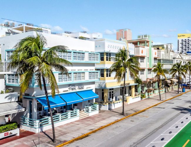 A vibrant street with colorful buildings, palm trees, and a bike lane under a clear sky.
