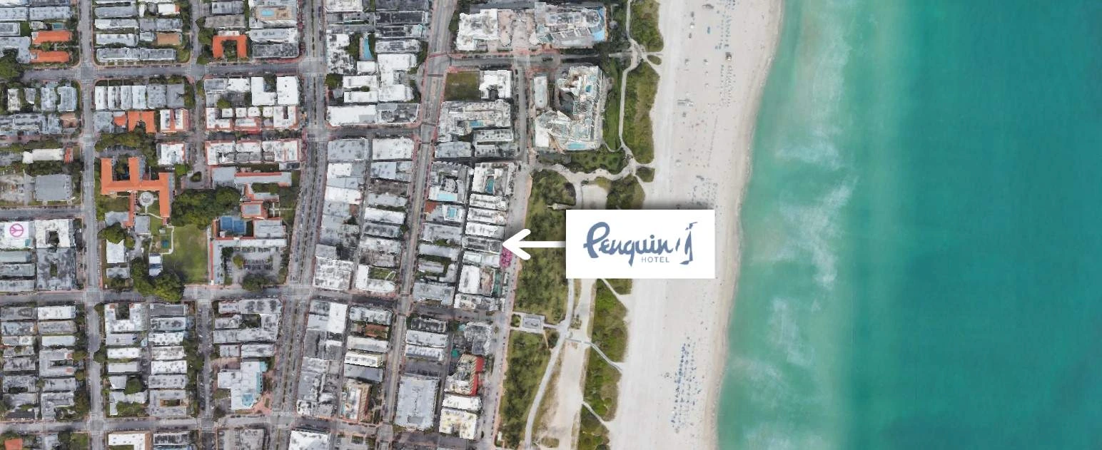 This image shows an aerial view of a coastal city with buildings and a beach, featuring a marker labeled “Penguin.”