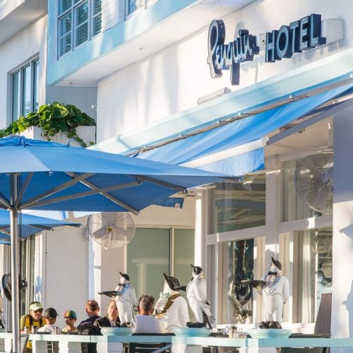 The image shows an outdoor cafe with blue umbrellas and the sign 