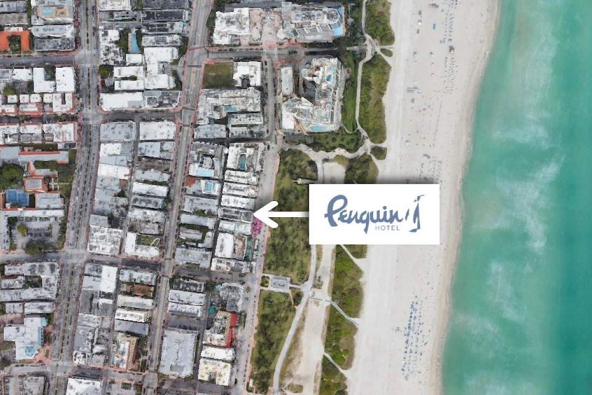 An aerial view of a coastal cityscape with a label pointing to "Penguin Hotel" near the beach and ocean on the right side of the image.